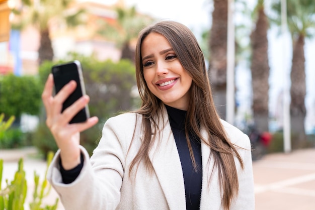 Junge hübsche Frau im Freien macht ein Selfie mit dem Handy