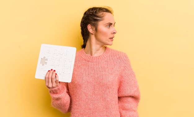 Junge hübsche Frau in der Profilansicht, die sich ein Puzzle-Konzept vorstellt oder träumt