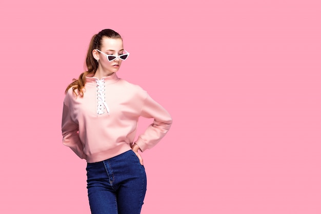 Junge hübsche Frau in der rosa Strickjacke und in der Sonnenbrille