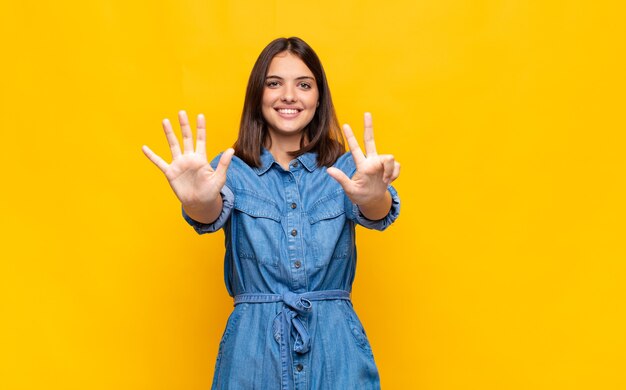 Junge hübsche Frau lächelt und sieht freundlich aus, zeigt Nummer acht oder acht mit der Hand nach vorne, Countdown