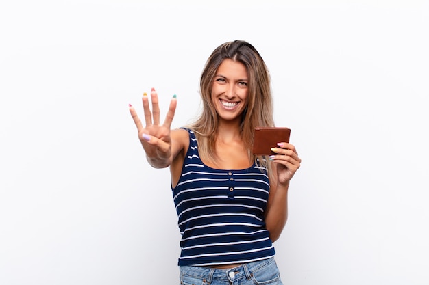 Junge hübsche Frau lächelt und sieht freundlich aus, zeigt Nummer vier oder viertens mit der Hand nach vorne und zählt mit einer Lederbrieftasche herunter.