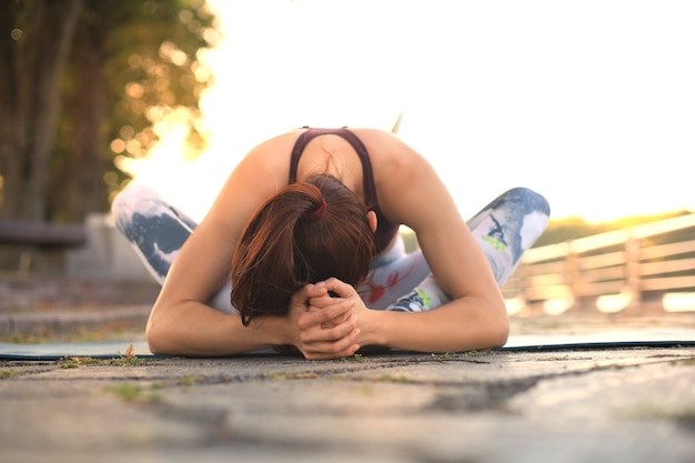 Junge hübsche Frau macht Yoga-Übungen im Park.