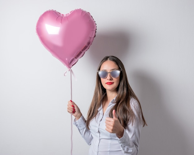 Junge hübsche Frau mit einem herzförmigen Luftballon