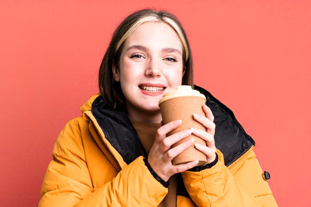 Junge hübsche Frau mit einem Mantel und einem Kaffee zum Mitnehmen