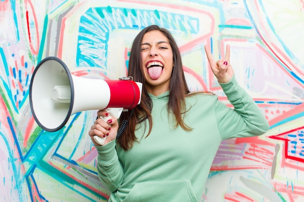 Junge hübsche Frau mit einem Megaphon gegen Graffitiwand