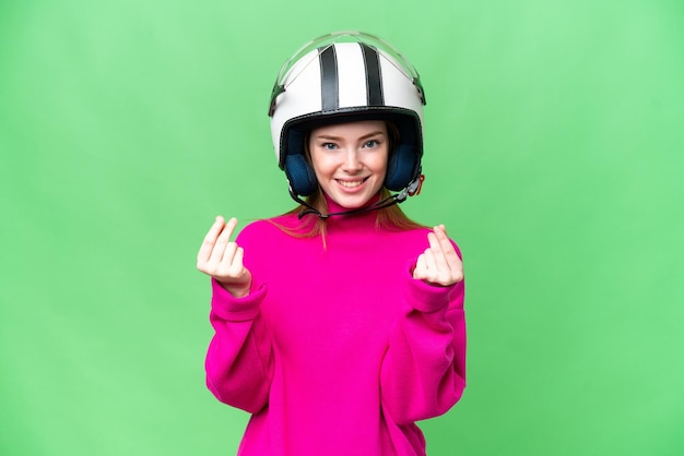 Junge hübsche Frau mit einem Motorradhelm über isoliertem Chroma-Key-Hintergrund, die Geldgeste macht