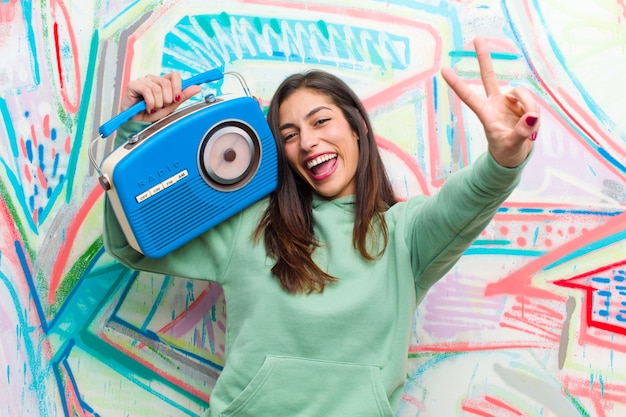 Foto junge hübsche frau mit einem weinleseradio gegen graffitiwand