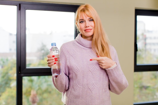 Junge hübsche Frau mit einer Wasserflasche zu Hause