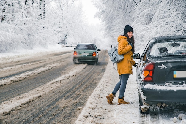 Junge hübsche Frau öffnet am Straßenrand Autotür Snowstor geparkt