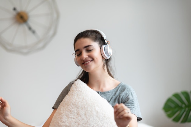 Junge hübsche Frau Person sind glücklich und genießen Sie mit Musik, indem Sie Kopfhörer verwenden, um ein Tonaudio im Schlafzimmer zu Hause zu hören, entspannen Sie sich und genießen Sie den Lebensstil mit einem Song-Melodie-House-Entertainment-Headset-Konzept