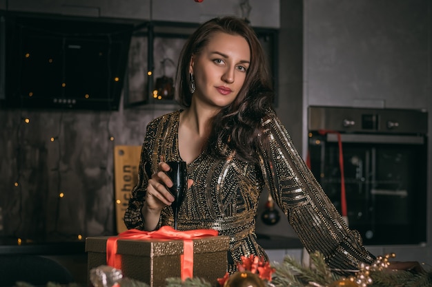 Junge hübsche Frau schließen oben mit schwarzem Glas Champagner auf dem festlichen Dekorationshintergrund. Weihnachtsfoto.