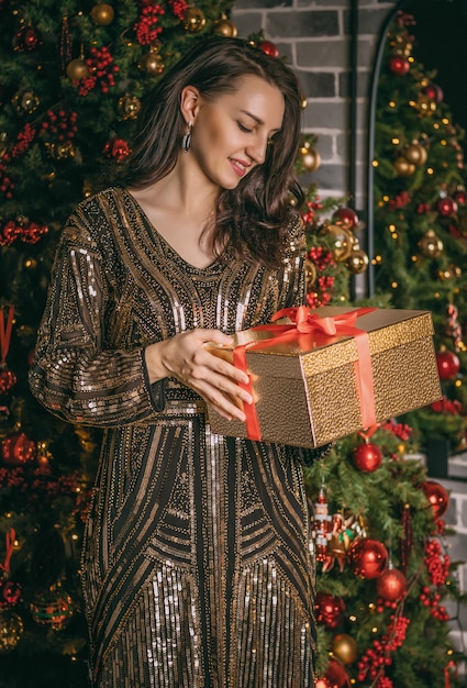 Junge hübsche Frau schließen oben unter dem festlichen Tannenbaum drinnen mit den Kisten der Geschenke. Weihnachtsfoto.