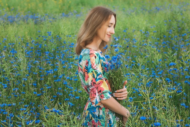 Junge hübsche Frau unter dem Feld der schönen Kornblumen