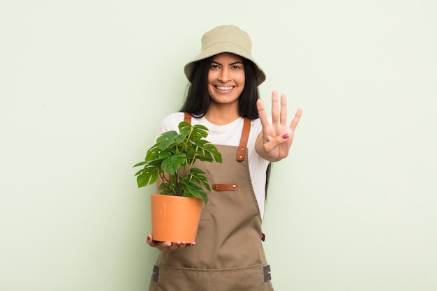 Junge hübsche hispanische Frau, die lächelt und freundlich aussieht und das Konzept des Landwirts oder Gärtners Nummer vier zeigt