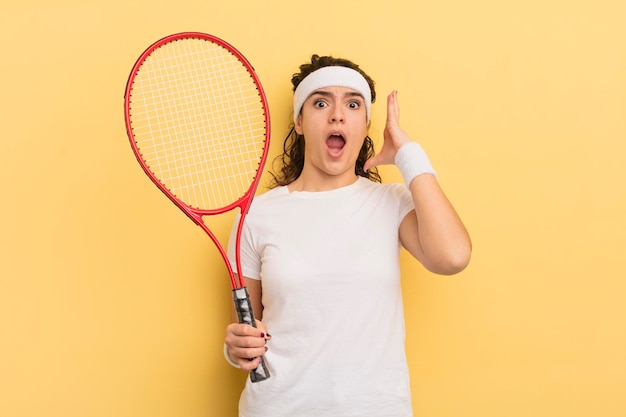 Junge hübsche hispanische Frau, die mit erhobenen Händen im Air-Tennis-Konzept schreit