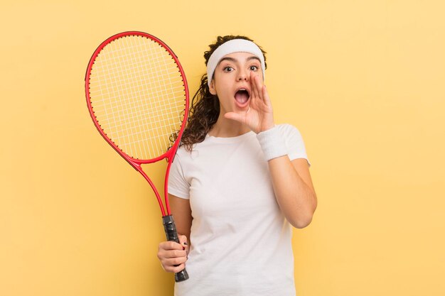 Junge hübsche hispanische frau, die sich glücklich fühlt und mit den händen neben dem mundtenniskonzept einen großen schrei gibt