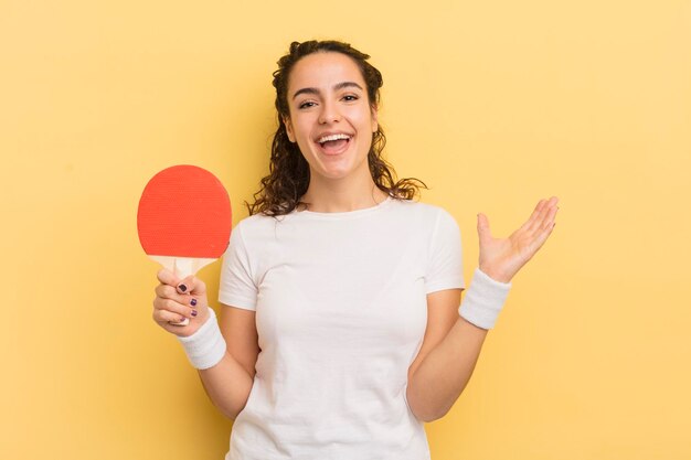 Junge hübsche hispanische Frau, die sich glücklich und erstaunt über etwas unglaubliches Ping-Pong-Konzept fühlt