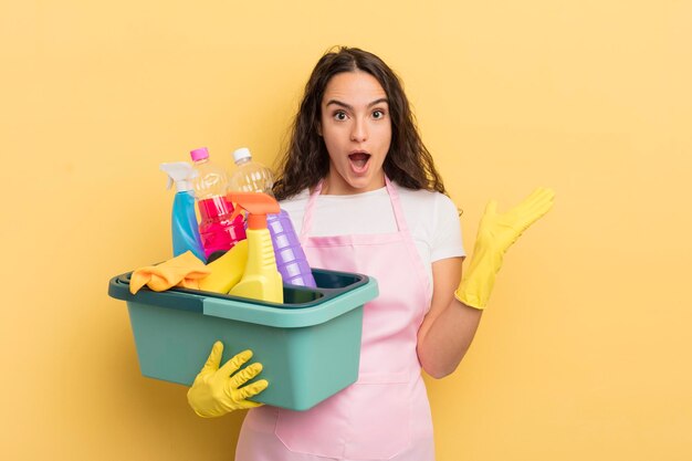 Junge hübsche hispanische Frau, die sich über etwas Unglaubliches glücklich und erstaunt fühlt. hausarbeit ein konzept für saubere produkte