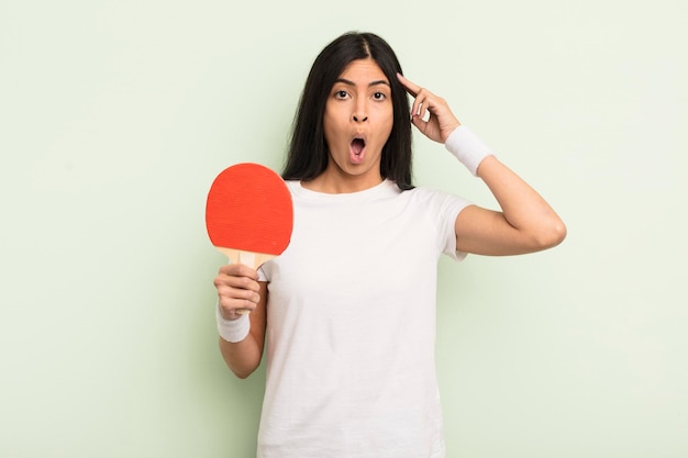 Junge hübsche hispanische Frau, die überrascht aussieht, als sie eine neue Gedankenidee oder ein Konzept-Ping-Pong-Konzept realisiert