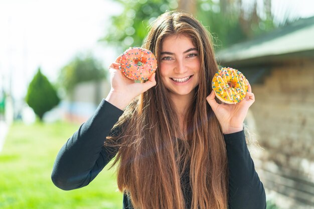 Junge hübsche kaukasische Frau hält Donuts mit fröhlichem Gesichtsausdruck