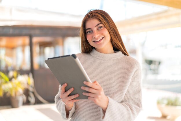 Junge hübsche kaukasische Frau hält ein Tablet mit fröhlichem Gesichtsausdruck