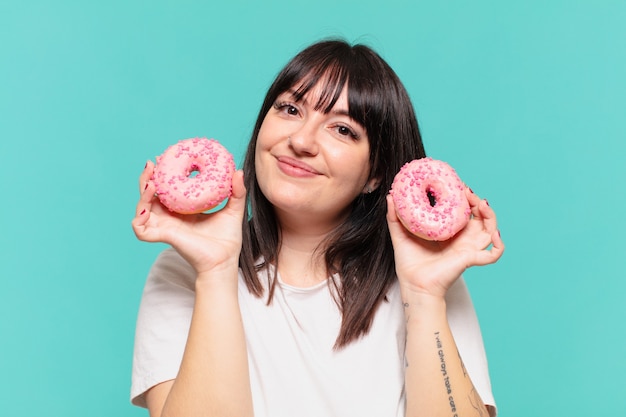 Junge hübsche kurvige Frau glücklicher Ausdruck und hält einen Donut