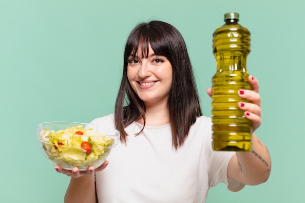 Junge hübsche kurvige Frau glücklicher Ausdruck und hält einen Salat