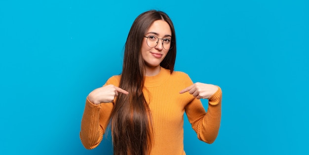 Junge hübsche lässige Frau, die stolz, positiv und lässig aussieht und mit beiden Händen auf die Brust zeigt