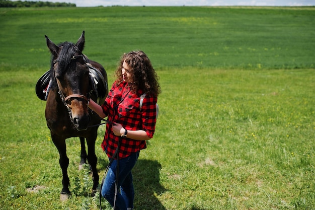 Junge hübsche Mädchen bleiben am sonnigen Tag mit Pferd auf einem Feld