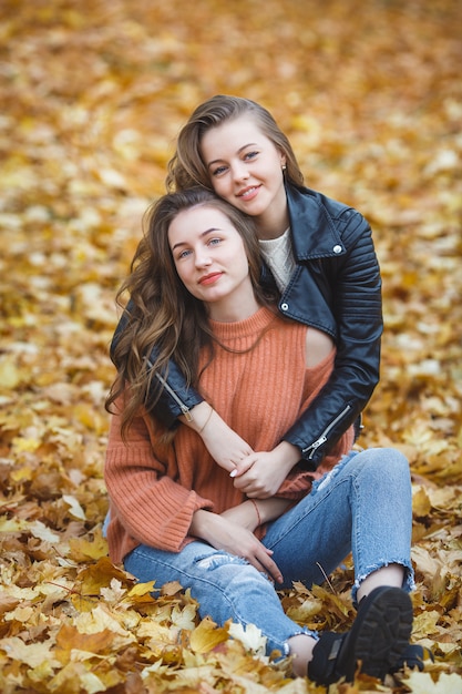 Junge hübsche Mädchen, die Spaß draußen im Herbsthintergrund haben. Fröhliche Freunde im Herbst