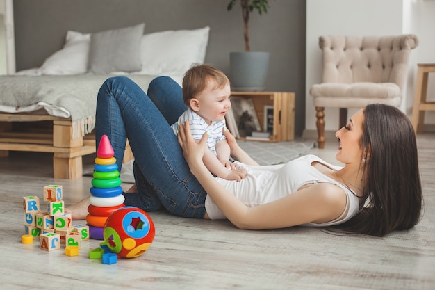 Junge hübsche Mutter, die mit ihrem kleinen Sohn spielt. Nette Familie, die Spaß zuhause mit kleinem Babysohn hat