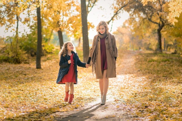 Junge hübsche Mutter mit ihrer kleinen Tochter, die Spaß im Herbst hat