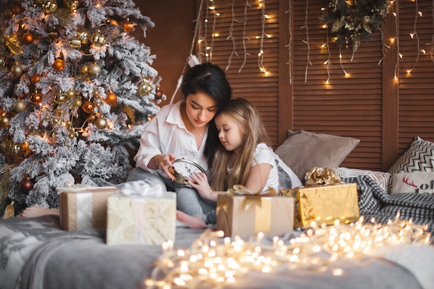 Junge hübsche Mutter und ihre kleine Tochter teilen Weihnachtsgeschenke