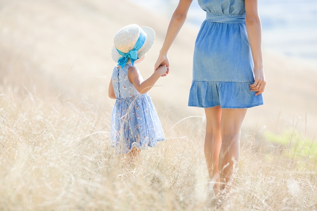 Junge hübsche Mutter und ihre Tochter draußen. Nahaufnahmeporträt der glücklichen Familie auf wildem Naturfeld. Mädchen, die Spaß haben.