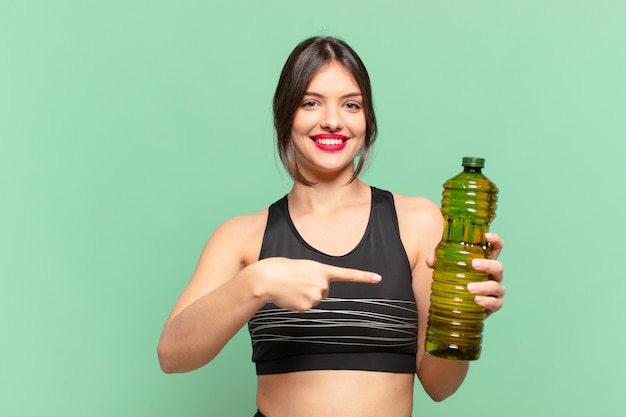 Junge hübsche Sportfrau, die eine Ölflasche zeigt oder zeigt und hält