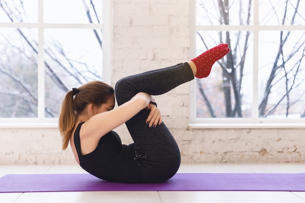 Junge hübsche sportliche Yogafrau in einer Haltung Kopf zum Knie