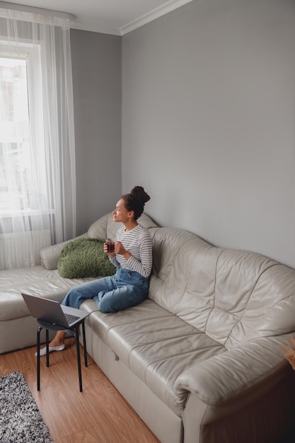 Junge hübsche stilvolle Frau, die zu Hause eine Kaffeepause von der Arbeit hat Freelancer Rest