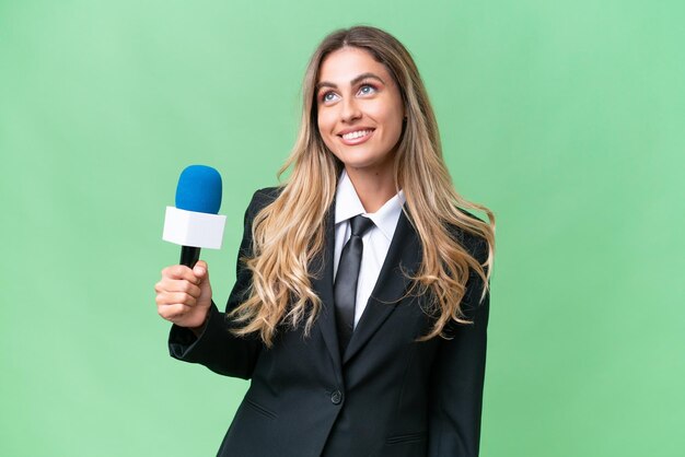 Junge hübsche uruguayische Fernsehmoderatorin mit isoliertem Hintergrund denkt beim Aufblicken über eine Idee nach