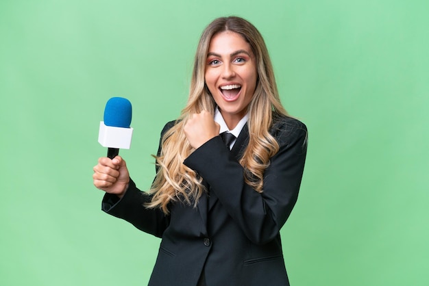 Junge hübsche uruguayische Fernsehmoderatorin vor isoliertem Hintergrund, die einen Sieg feiert