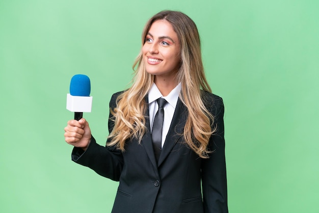 Junge hübsche uruguayische Fernsehmoderatorin vor isoliertem Hintergrund, die zur Seite schaut und lächelt