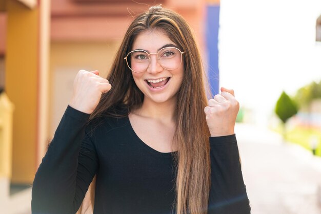 Foto junge, hübsche weiße frau mit brille, die einen sieg feiert