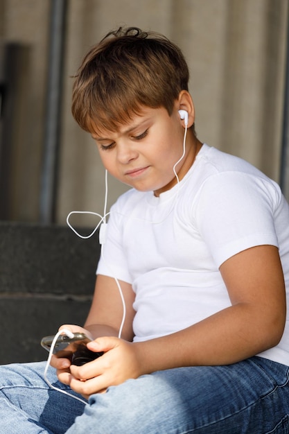 Junge im Kopfhörer mit Smartphone hört Musik im Sommerpark