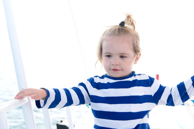 Junge im Matrosenhemd segeln im blauen Meer Kind mit blonden Haaren auf der Yacht an einem sonnigen Tag Sommerurlaubskonzept Reiseziel Kreuzfahrtreisen Abenteuer Entdeckung Fernweh