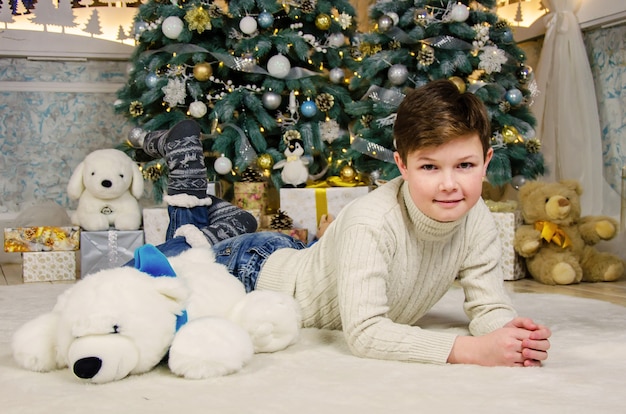 Junge in der Nähe des Weihnachtsbaumes zu Weihnachten mit Spielzeug