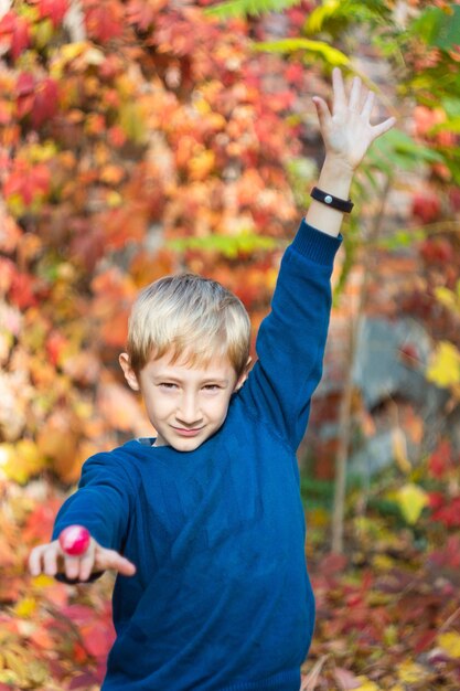 Junge in einer blauen Jacke auf dem Hintergrund einer Herbstlandschaft