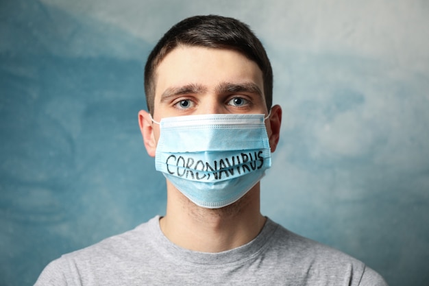 Junge in Schutzmaske mit Inschrift Coronavirus auf blau.