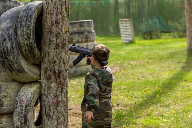 Junge in Tarnkleidung spielt Lasertag auf einem speziellen Waldspielplatz