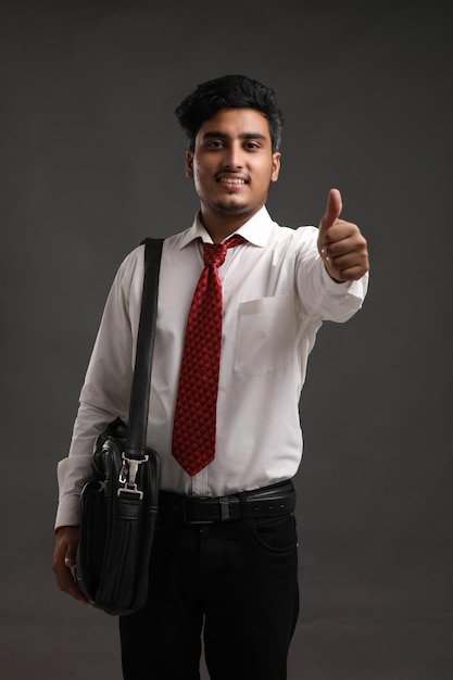 Foto junge indische banker oder geschäftsmann mit ausdruck auf dunklem hintergrund.