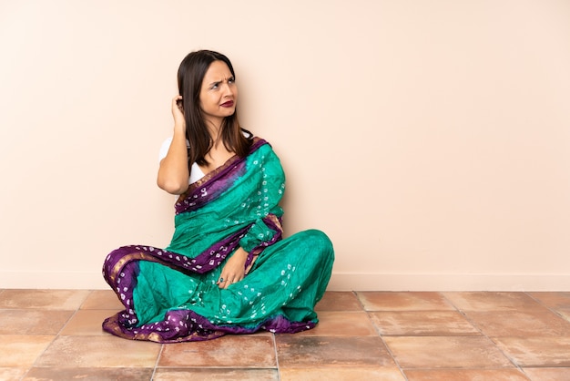 Junge indische Frau, die auf dem Boden sitzt