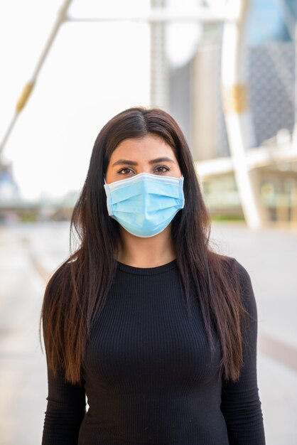 Junge indische Frau, die Maske zum Schutz vor Coronavirus-Ausbruch an der Skywalk-Brücke trägt